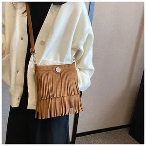 Detail view of a brown suede tassel crossbody bag with vintage bohemian metal decor