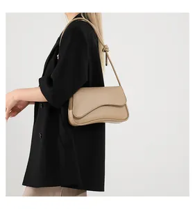 Detail der beige Schultertasche mit wellenförmiger Klappe und modischem Knotengurt