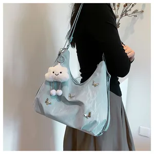 Détail d'un sac hobo bleu clair à papillons avec charme nuage en peluche et touches argent