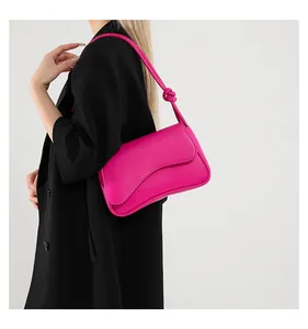 Detail der pinkfarbenen Schultertasche mit Knotengurt und gewelltem Klappendesign