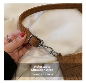 Detailed close-up of brown suede bag adjustable shoulder strap with silver metal hardware