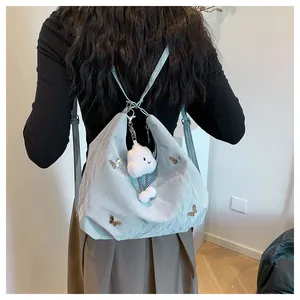 Détail du sac cabas papillon bleu clair avec texture froissée et breloque nuage peluche
