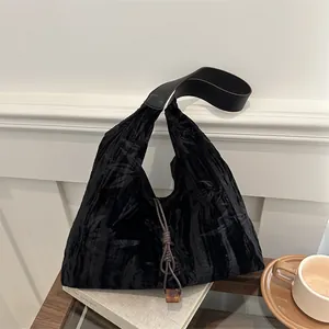 Large black velvet tote bag with plant leaf texture and a wide leather shoulder strap