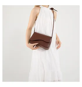 Detail der dunkelbraunen Klapptasche mit Wellenkanten an Model in weißem Kleid