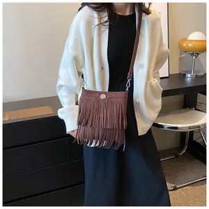 Close-up of brown fringe crossbody bag with suede finish and metallic round buckle