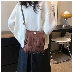 Detail of brown suede crossbody bag with long fringes shown on a model