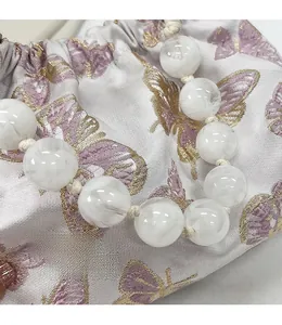 Detail der Satin-Beuteltasche mit Schmetterlingsstickerei und großem Perlengriff