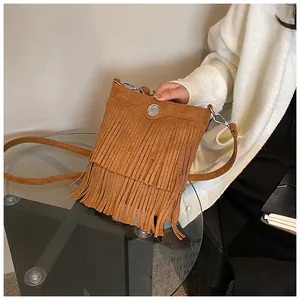 Close-up of brown suede crossbody bag featuring tiered fringe and silver metal buckle