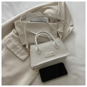 Detailed macro view of white textured leather bag with gold fashion metal logo