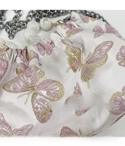 Detail aus rosa Satinstoff mit feiner goldener Schmetterlingsstickerei und Perlenstrauch