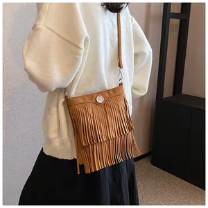 Close-up of brown suede crossbody bag featuring tiered fringe details and silver logo