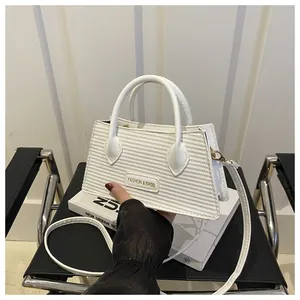 Close-up of white crossbody bag with textured embossing and Fashion & Bags plaque