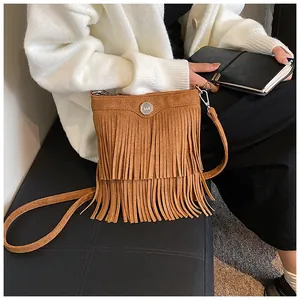 Detail of vintage brown suede crossbody bag with long tassels and metallic magnetic buckle