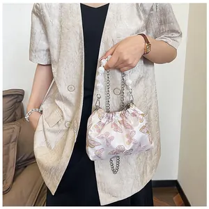 Detail der rosa Satin-Beuteltasche mit Perlenriff und Schmetterlingsstickerei am Modell