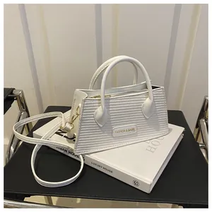 Close-up of white crossbody bag showing woven texture and gold hardware details