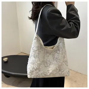 Détail d'un sac cabas blanc avec broderie papillon 3D porté sur une veste de blazer noire