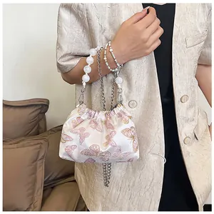 Detail der rosa Schmetterlingsstickerei auf einer Cloud-Bag mit Perlen- und Kettenriemen