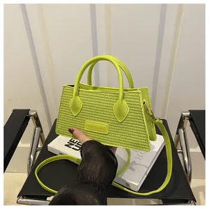 Detail of neon green woven handbag with Fashion & Bags metal logo plate and strap