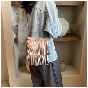 Brown suede crossbody bag with vintage fringe details shown in a casual lifestyle setting
