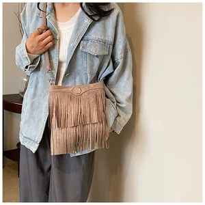 Close-up of brown suede crossbody bag with long double tassels and gold metal detail