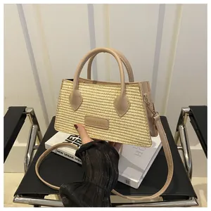 Detail of woven straw handbag featuring a beige leather trim and brand logo label