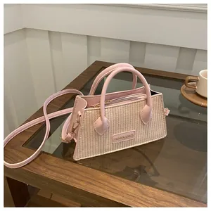 Detail of pink woven texture handbag with detachable strap and golden metal hardware