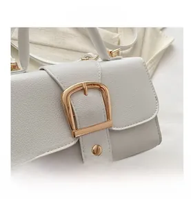 Detail of white lychee grain leather handbag with gold metal clasp and neat stitching