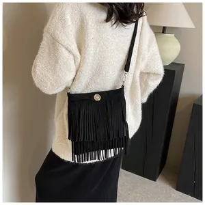 Detail of bohemian black crossbody bag featuring long fringes and round metal buckle detail