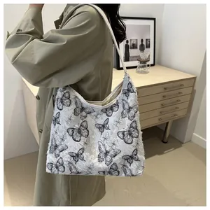 Détail d'un sac cabas en toile avec motifs de papillons en dentelle noire texturée