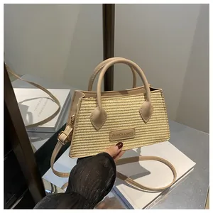 Detail of woven straw handbag with light beige leather handles and fashion logo