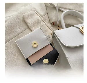 Macro detail of white lychee leather mini bag charm with golden magnetic buckle