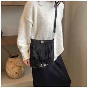 Detail of black suede crossbody bag with long double-layer fringe and metal M logo