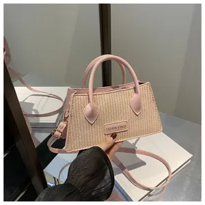 Detail of pink woven crossbody bag with leather handle and fashion logo plate