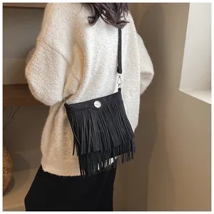 Close-up of black fringe crossbody bag with silver hardware and suede texture