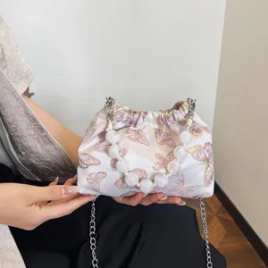 Nahaufnahme von Schmetterling-Jacquard-Stoff und Perlen-Handgriff an der Handtasche