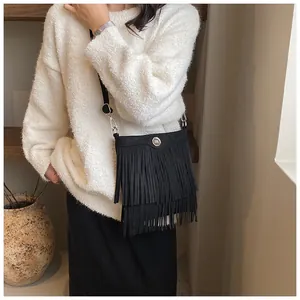 Detail of black suede crossbody bag with double-layer fringe and silver 'm' metal buckle