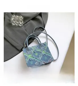Gros plan du mini sac en jean bleu avec bords francs et broderie étoile verte détaillée