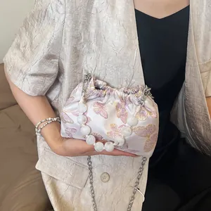 Detail der eleganten Satin-Beuteltasche mit rosa Schmetterlingsstickerei und Perlengriff