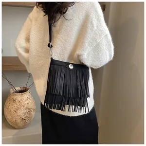 Detail of a vintage black fringe crossbody bag featuring matte texture and silver hardware