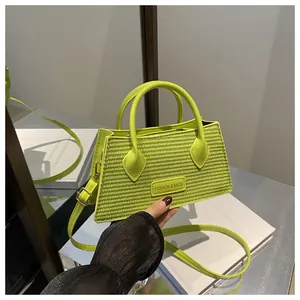 Detail of neon green woven handbag featuring metallic brand plate and textured handle