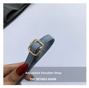 Détail d'une bandoulière réglable en denim bleu avec boucle en métal doré sur le sac