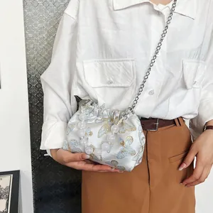 Detail der hellblauen Satin-Beuteltasche mit goldener Schmetterlingsstickerei und Perlen