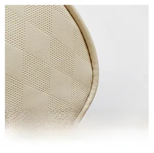 Close-up of beige leather handbag featuring geometric diamond quilting and micro-perforations