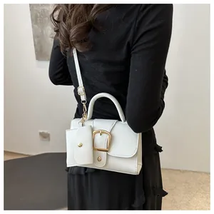 Detail of white leather crossbody bag with gold buckle and mini coin purse attachment