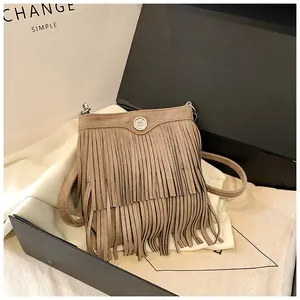 Macro detail of brown suede fringe crossbody bag with metallic logo on silk fabric