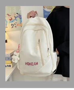 Detail of a beige high-capacity backpack with HOKEAM logo and a plush bear charm