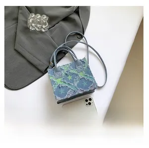 Mini sac à main en jean avec écusson étoile et bandoulière montré à côté d'un téléphone