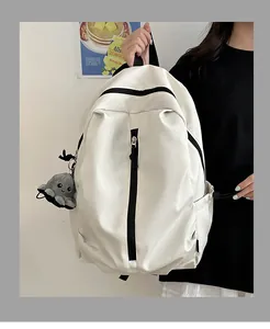 Detail eines cremeweißen Rucksacks mit schwarzen Reißverschlüssen und Oktopus-Anhänger