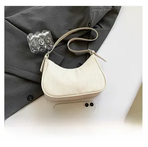 Top view of cream crescent crossbody bag with quilted texture and adjustable strap