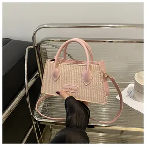 Detail of pink straw and leather handbag with dual handles and elegant brand plate